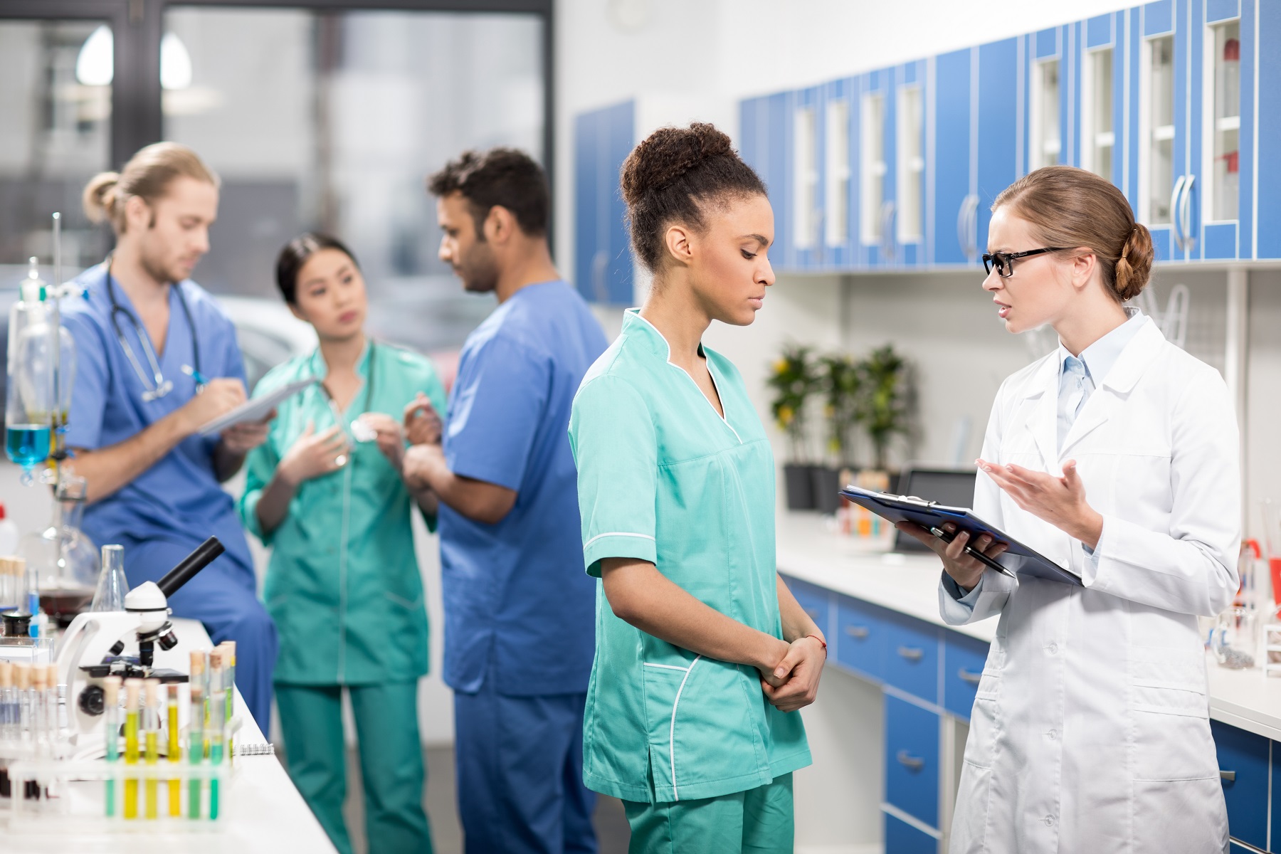 medical workers discussing work with colleagues behind in laboratory
